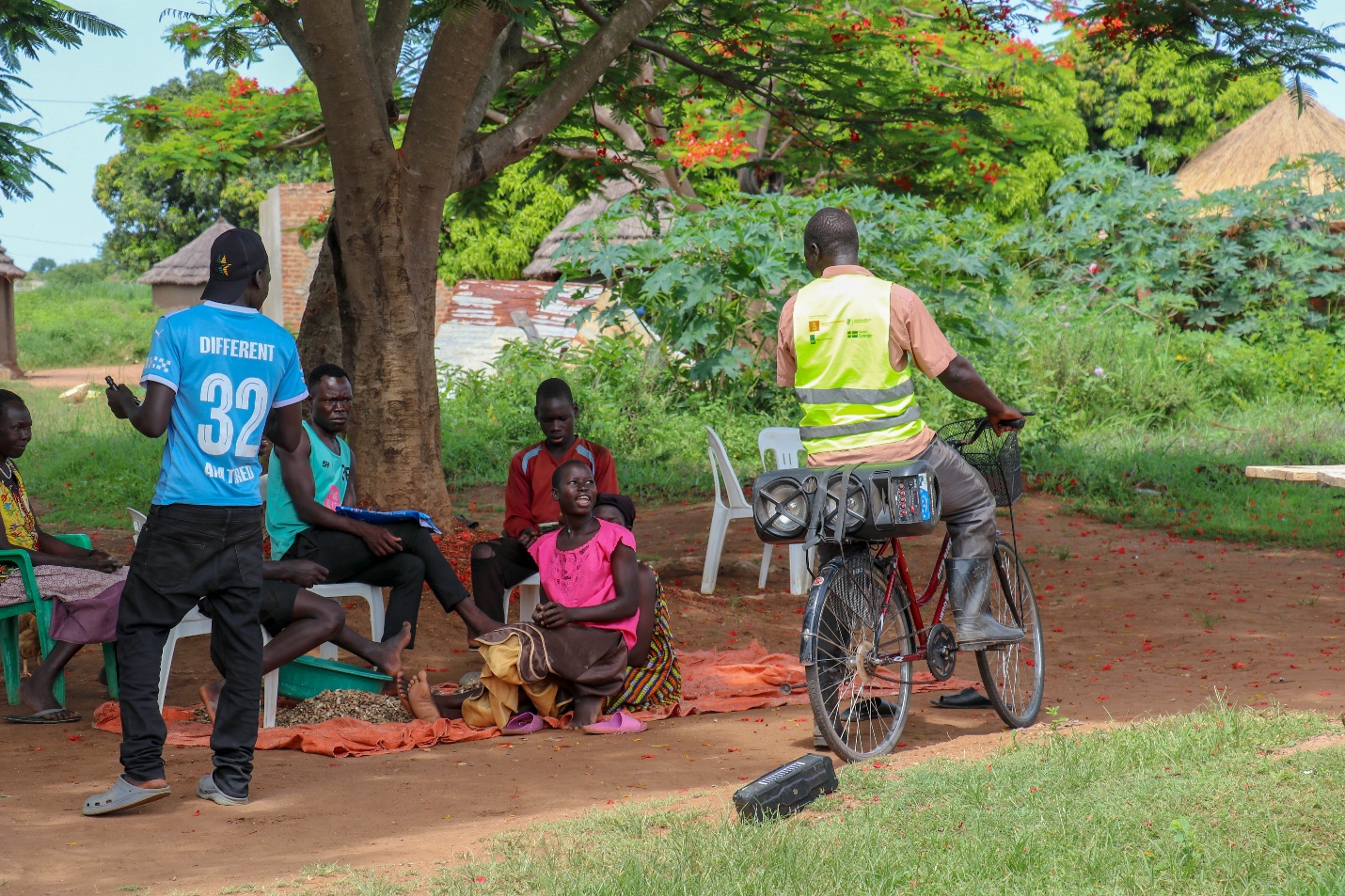 Iya Samuel uses the bicycle and portable public address system provided by the project to broadcast prerecorded messages on climate justice to a group of youth and women. Photo Credit: Wairimu Veronicah - RICE West Nile